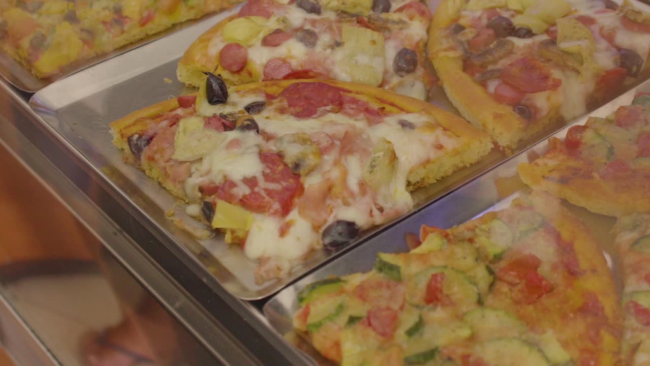 deliciosas rebanadas de focaccia y pizza en un mostrador de panadería italiana, cámara lenta de cerca