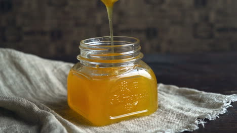 honey jar with dripper. honey bowl on table. honey dripping in bottle