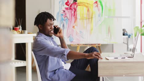 Artista-Masculino-Afroamericano-Hablando-Por-Teléfono-Inteligente-En-El-Estudio-De-Arte