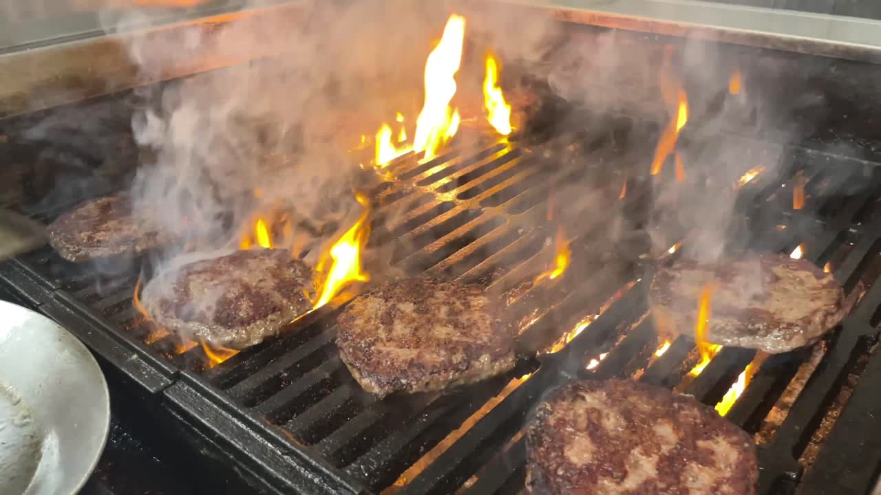 cooking burgers on a flame grill in a restaurant kitchen
