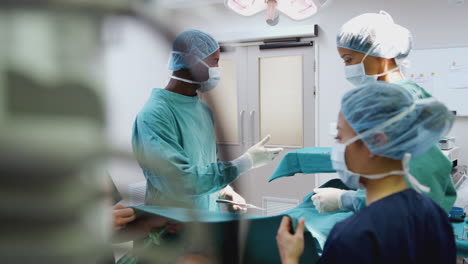 nurse hands surgeon medical instruments as surgical team work on patient in operating theatre