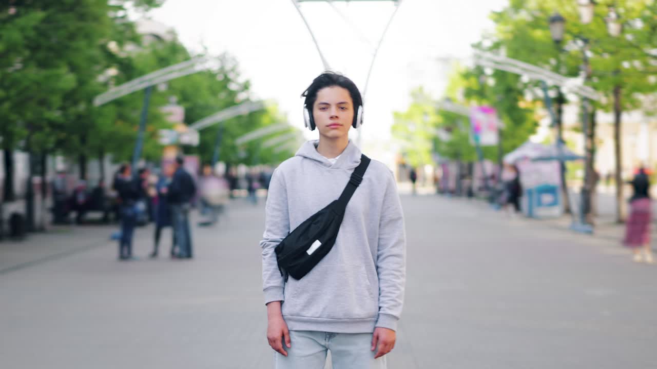 Time-lapse portrait of teenager in headphones standing outdoors in the street
