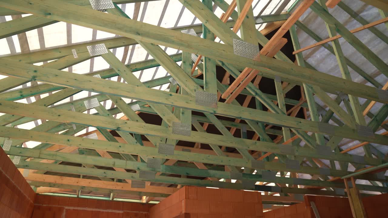 Wooden roof trusses and beams installed on new house under construction