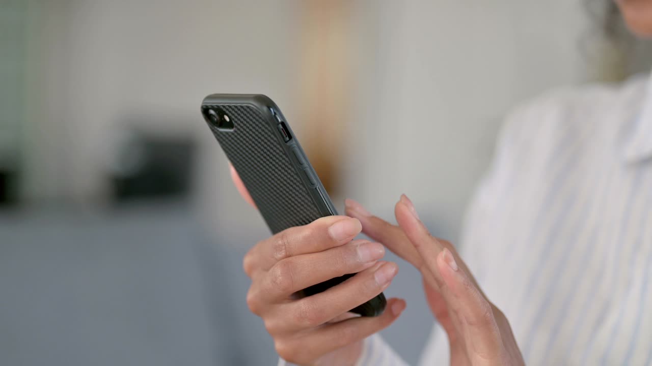 cerca de las manos de una mujer de negocios africana usando un teléfono inteligente