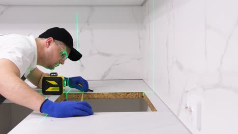 a builder in uniform performs quality control of furniture installation in a new apartment use of an a builder in uniform performs quality control of furniture installation in a new apartment the concept of construction and repair use of an electronic construction laser