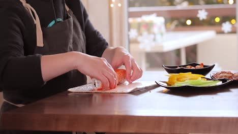 hacer sushi en la cocina de casa. manos de mujer enrollando sushi casero.