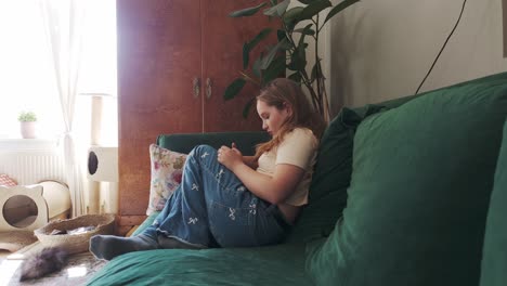 young girl using mobile phone while relaxing on living room sofa