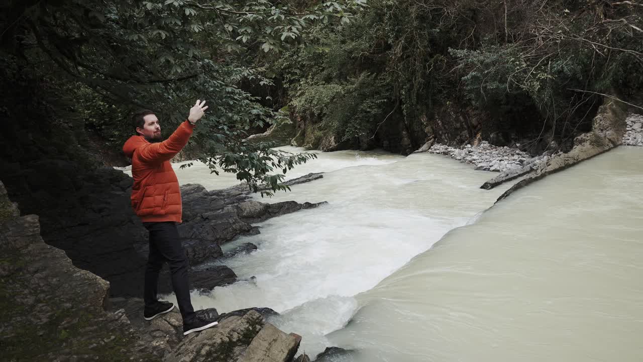 hombre tomando una foto de una cascada en un bosque