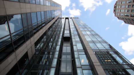 exploring modern architecture: a stunning view of a sleek glass building stretching towards the sky with reflections and a vibrant city backdrop