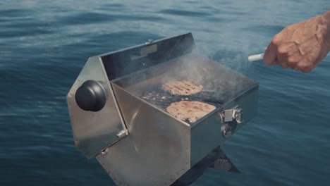 Hombre-Asando-A-La-Parrilla-En-Un-Bote-Mientras-Disfruta-De-Un-Día-En-El-Agua