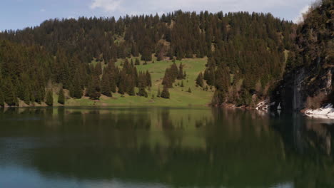 Passing-Swiss-flag-waving-near-beautiful-Lac-des-Chavononnes,-Switserland