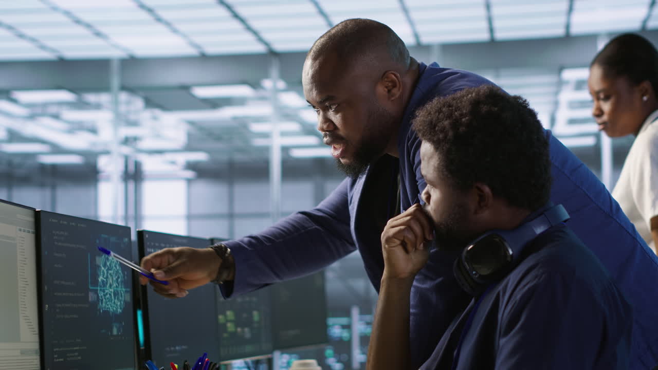 Two colleagues discussing data on computer screens in a modern office
