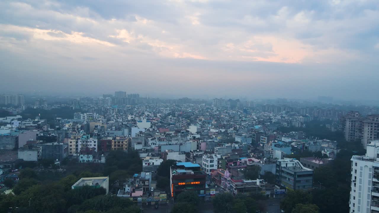 Ripresa aerea con drone che mostra la tranquilla vista mattutina di Delhi, con grattacieli e monumenti storici illuminati dalle fredde tonalità blu dell'alba.