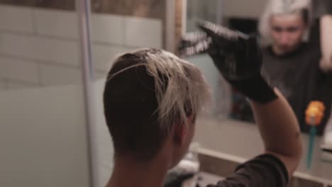 a young lady facing the mirror while fixing her bleached hair - close up shot