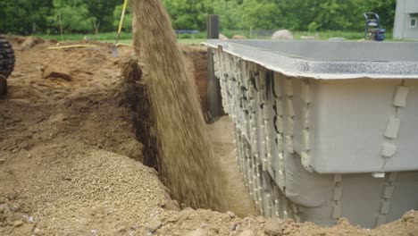 side view of crushed gravel poured to backfill fiberglass pool install in backyard