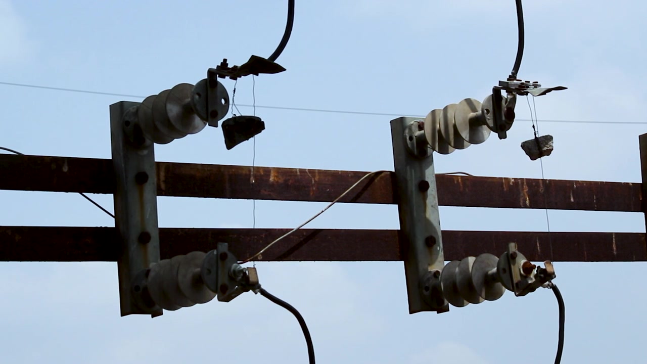 Close-up of high voltage disconnect switches and ceramic insulators used in electrical distribution systems, ideal for power grid, utility maintenance, energy infrastructure and transmission projects.