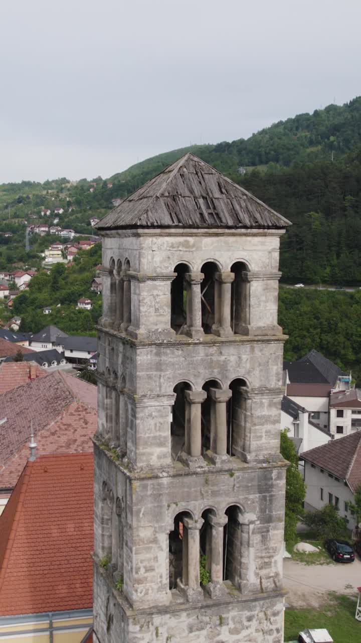 Drone view of Saint Mary's Church bell tower, a historical landmark in Jajce, Bosnia and Herzegovina, highlighting its architecture and weathered roof. Vertical Video