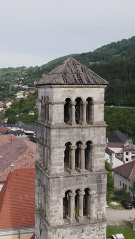 drone view of saint mary's church bell tower, a historical landmark in jajce, bosnia and herzegovina, highlighting its architecture and weathered roof. vertical video