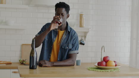 man drinking red wine in a kitchen