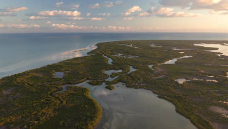 tropical coastline with rainforest, lakes and rivers below dusking sky