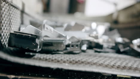 Machined metal car components falling down a shaker after being cleaned with sand
