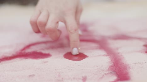 la tinta roja cae sobre el lienzo y los artistas usan las manos para pintar