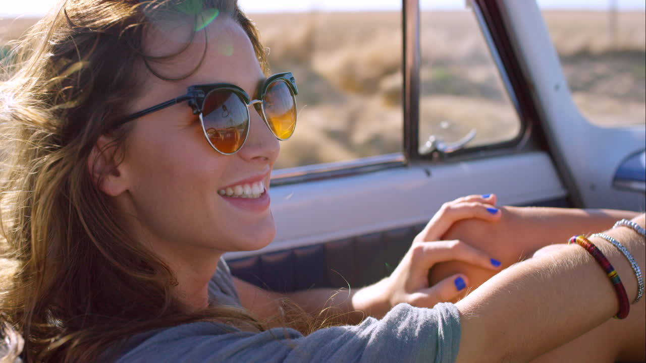 a cheerful young woman driving on a road in a car