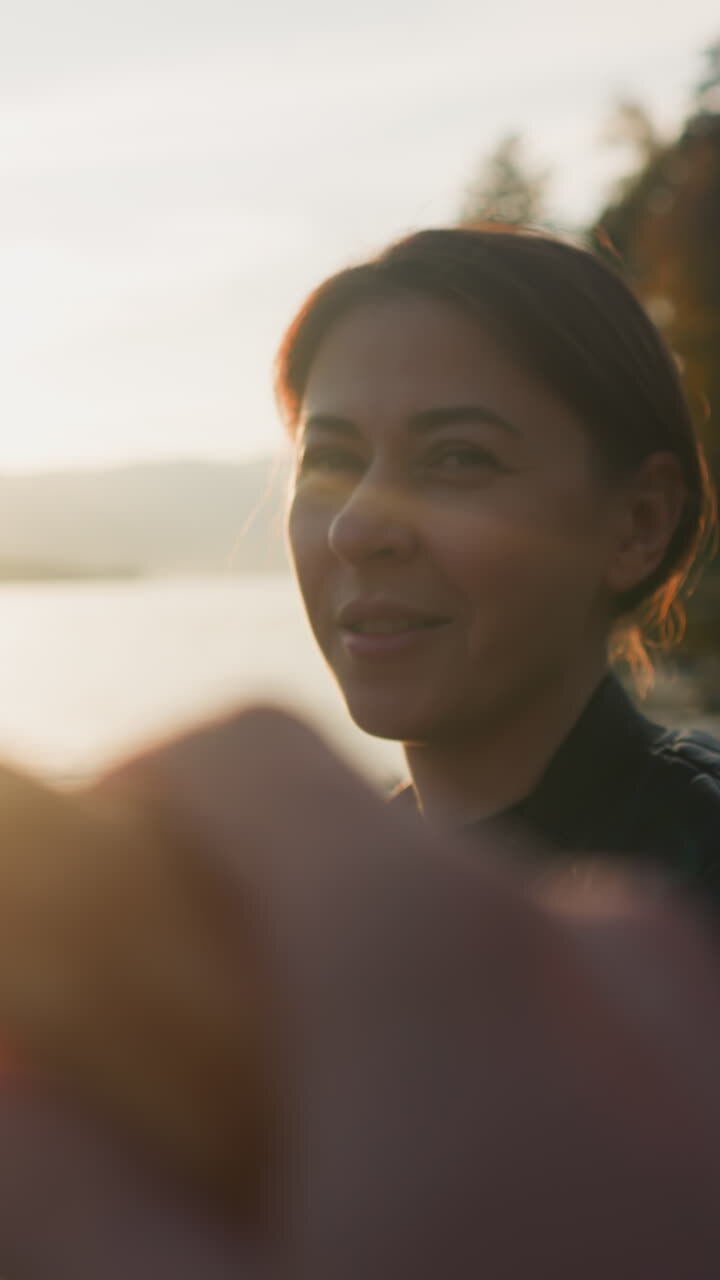 Man offers croissant to lady at sunset. Young people enjoy romantic picnic near lake on autumn evening together. Enjoying weekend with captivating sunset