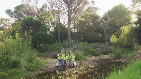 mid adults with yellow vest volunteering and cheering up during river clean-up day