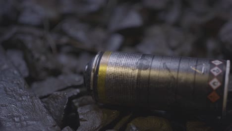 close-up of a graffiti spray can falling onto rocks as a train passes by at dusk