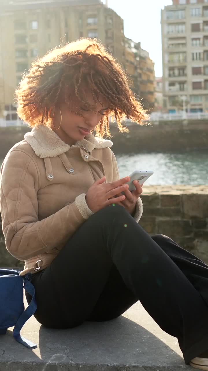 Mulher usando celular à beira do rio