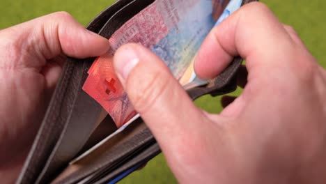 man opening purse and checking swiss franc banknotes,close up