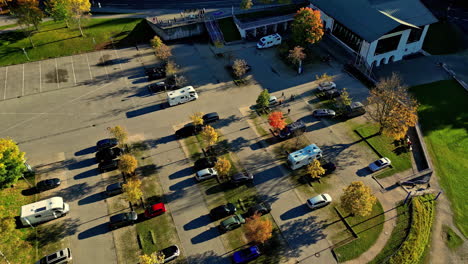 camper vans and cars parked in city suburb parking lot with trees