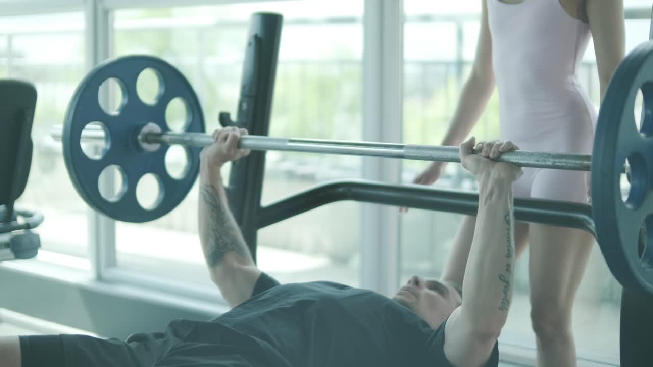 트레이너 와 함께 벤치 프레싱 하는 사람