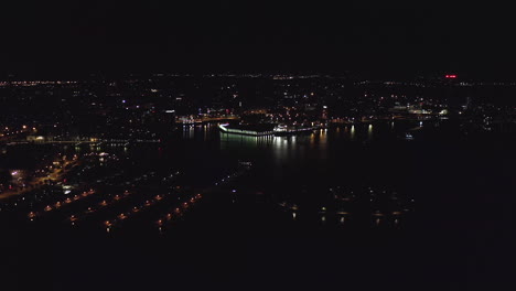 Aerial,-tracking,-drone-shot,-panning-around-the-Helsinki-north-harbor,-overlooking-Kruununhaka,-Tervasaari,-Merihaka-and-Sompasaari,-the-city-full-of-lights,-in-Uusimaa,-Finland