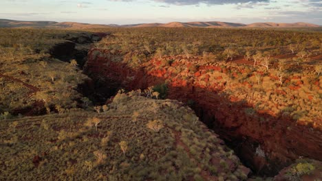 Aerial-orbit-shot-showing-Joffre-Falls-Gorge-in-Karijini-National-park-during-golden-sunset-in-Western-Australia