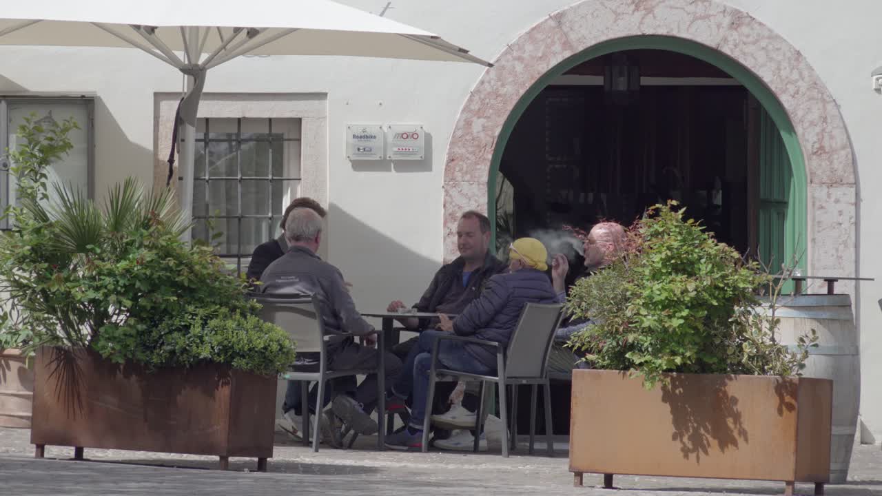Group of Men Chatting and Smoking at an Outdoor Cafe