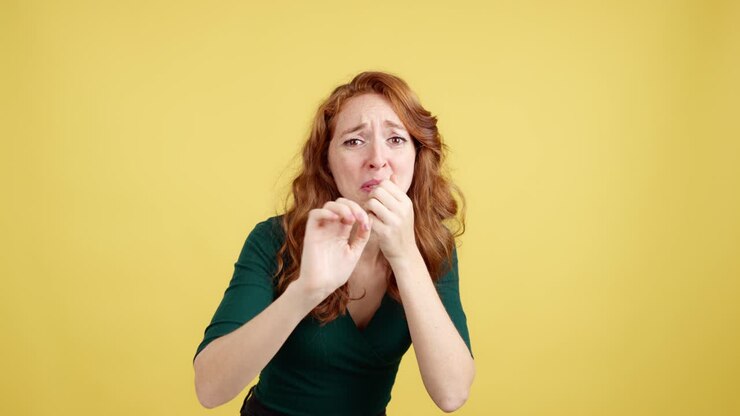 Donna dai capelli rossi che esprime paura e shock su sfondo giallo