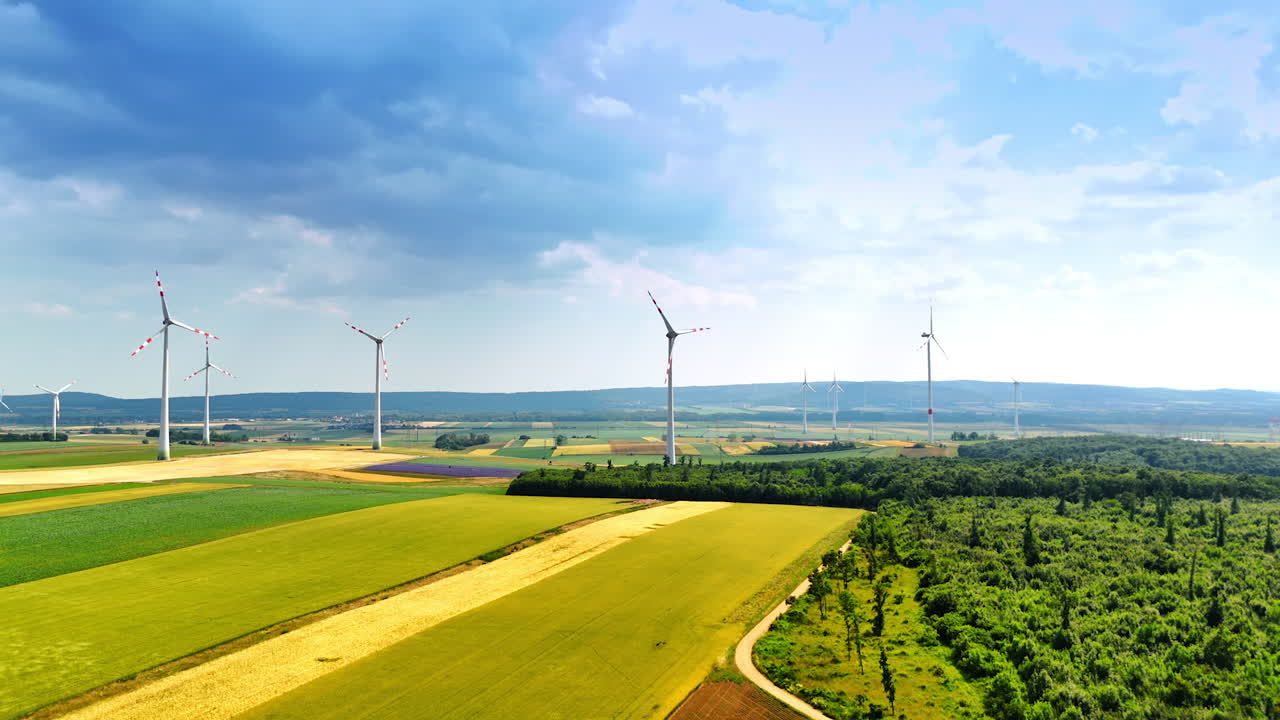 Wind turbines produce clean energy. Wind turbines stand tall in green fields under a cloudy sky, showcasing renewable energy production in rural landscapes