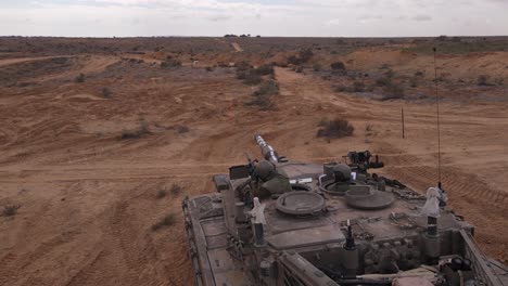 view of two soldiers firing ammunition on a military tank vehicle in a large military training field