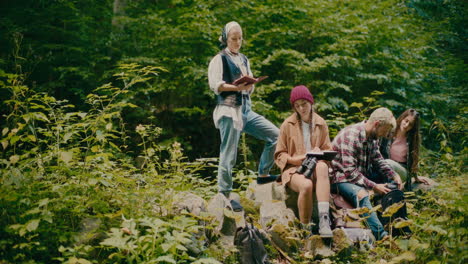 Freundinnen-Sitzen-Auf-Felsen-Inmitten-Von-Pflanzen-Im-Wald