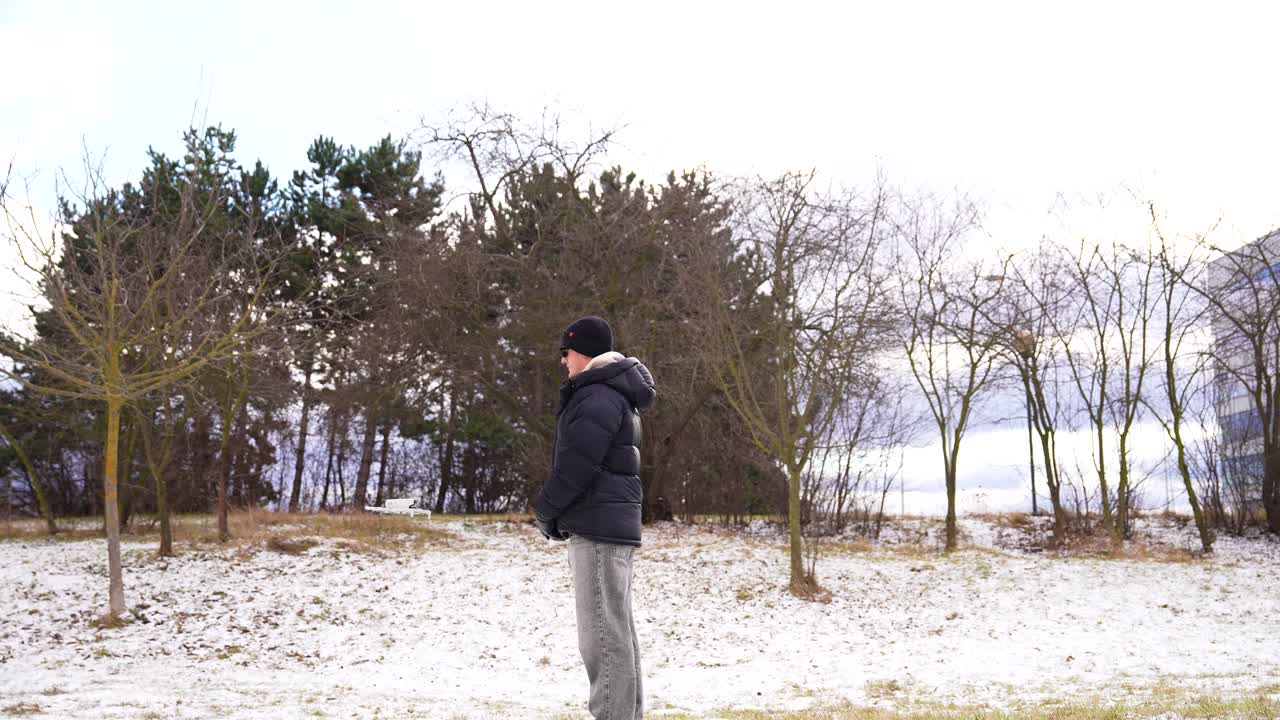 Man in winter clothes stand alone in snowy park and drone approach, Czechia