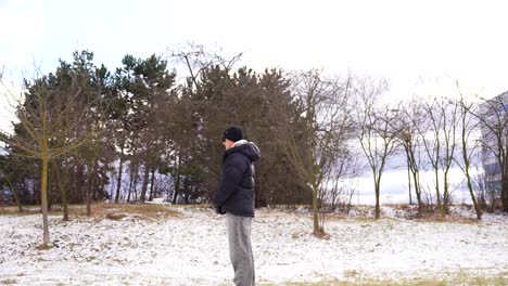 man in winter clothes stand alone in snowy park and drone approach, czechia