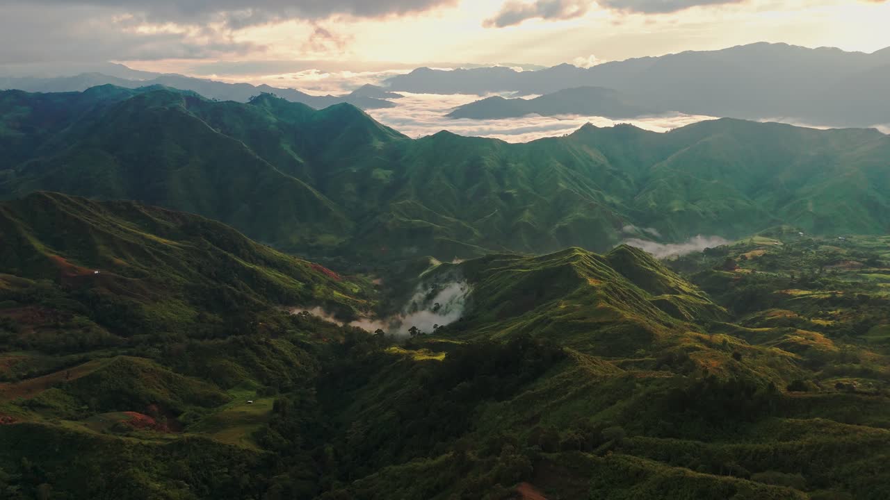 Drone shot of verdant mountain range at sunrise, with rolling fog, golden light, and dramatic shadows — ideal for cinematic, travel, or nature projects