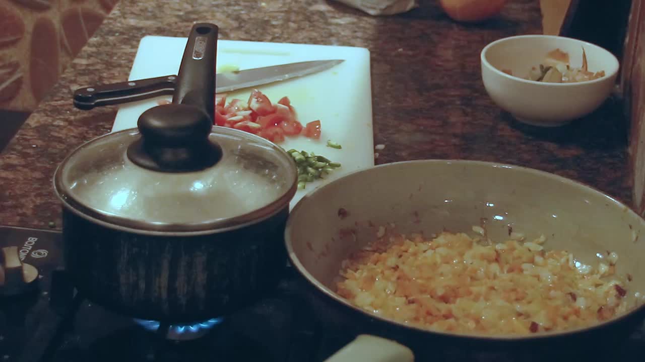 Sauteing ingredients in a pan that shows the process of home cooking and the mundane chores of domestic life