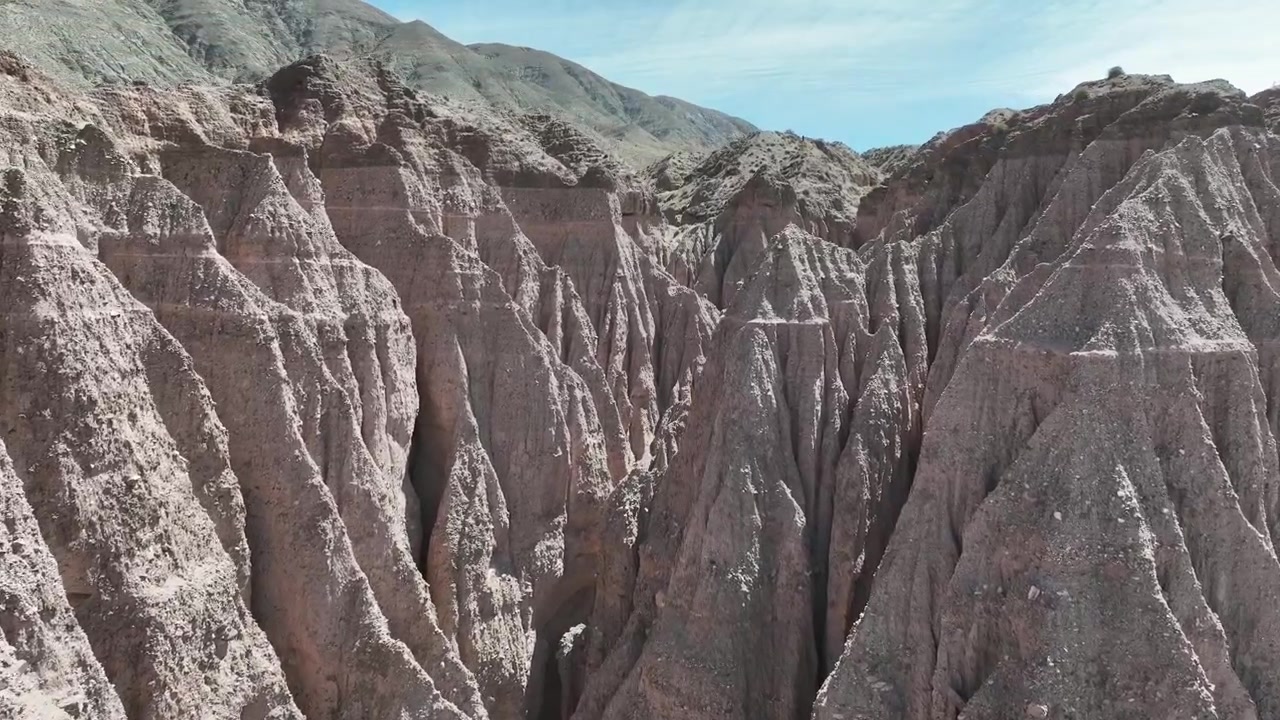 Volo fluido con drone sopra formazioni rocciose erose e burroni di argilla vicino a Purmamarca, Jujuy, Argentina. Strati geologici di argilla unici nella Quebrada de Humahuaca