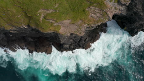 Los-Pájaros-Aéreos-Miran-Arriba-Hacia-Abajo-La-Vista-Ascendente-De-Las-Olas-ásperas-Rompiendo-En-La-Costa-Rocosa.-Hierba-Verde-En-La-Cima-De-Los-Acantilados-Por-Encima-Del-Agua-Clara.-Paseo-Del-Acantilado-De-Kilkee,-Irlanda