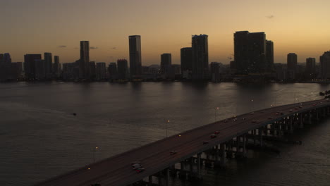 Miami-Bridge-with-cars-passing-by-With-Downtown-Miami-In-The-Background-at-Dusk-Aerial-Shot