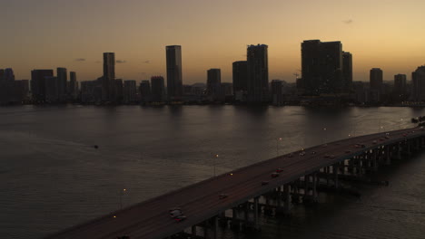 puente de miami con coches pasando con el centro de miami en el fondo en el atardecer tiro aéreo
