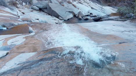 Antenne-Nahaufnahme-Eines-Wasserfalls,-Der-Eine-Granitfelswand-Hinunterfließt